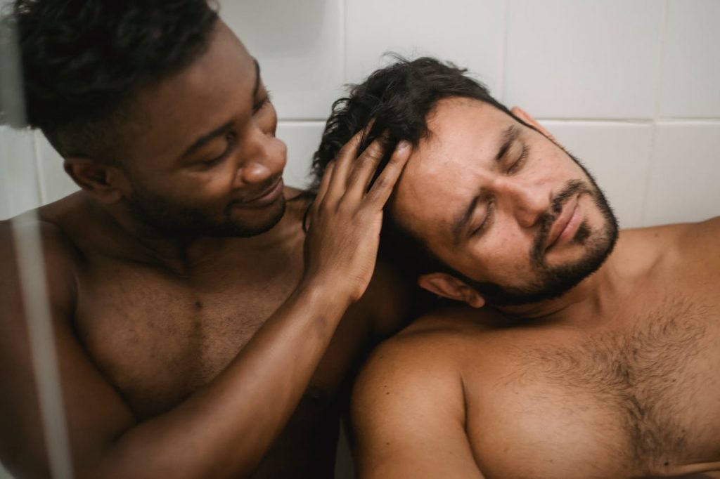 pexels photo 4830998 A tender, loving moment captured between two shirtless men sharing a private, intimate expression of affection.